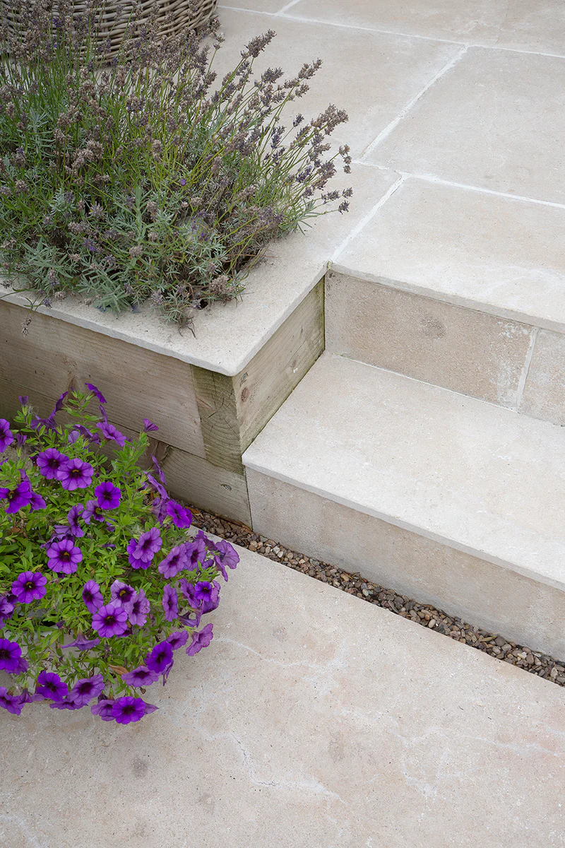 Porcelain patio with flush steps leading to a landscaped garden