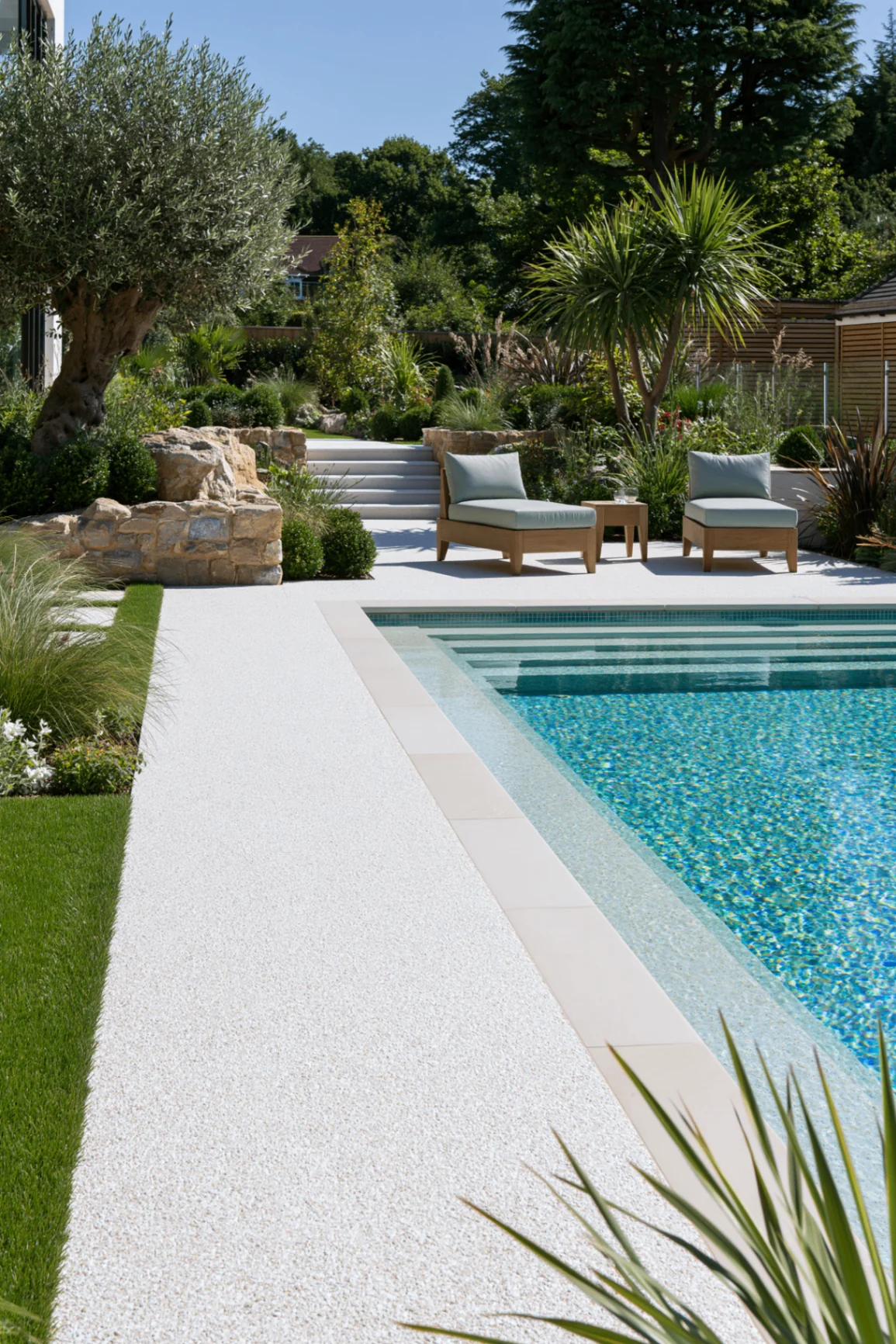 Light grey resin bound surface surrounding a garden swimming pool with lawn border